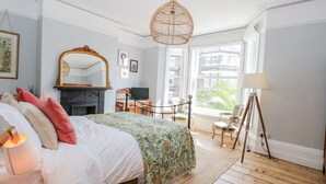 Een slaapkamer met een bed, een spiegel, een televisie, een lamp en uitzicht op het omliggende landschap.