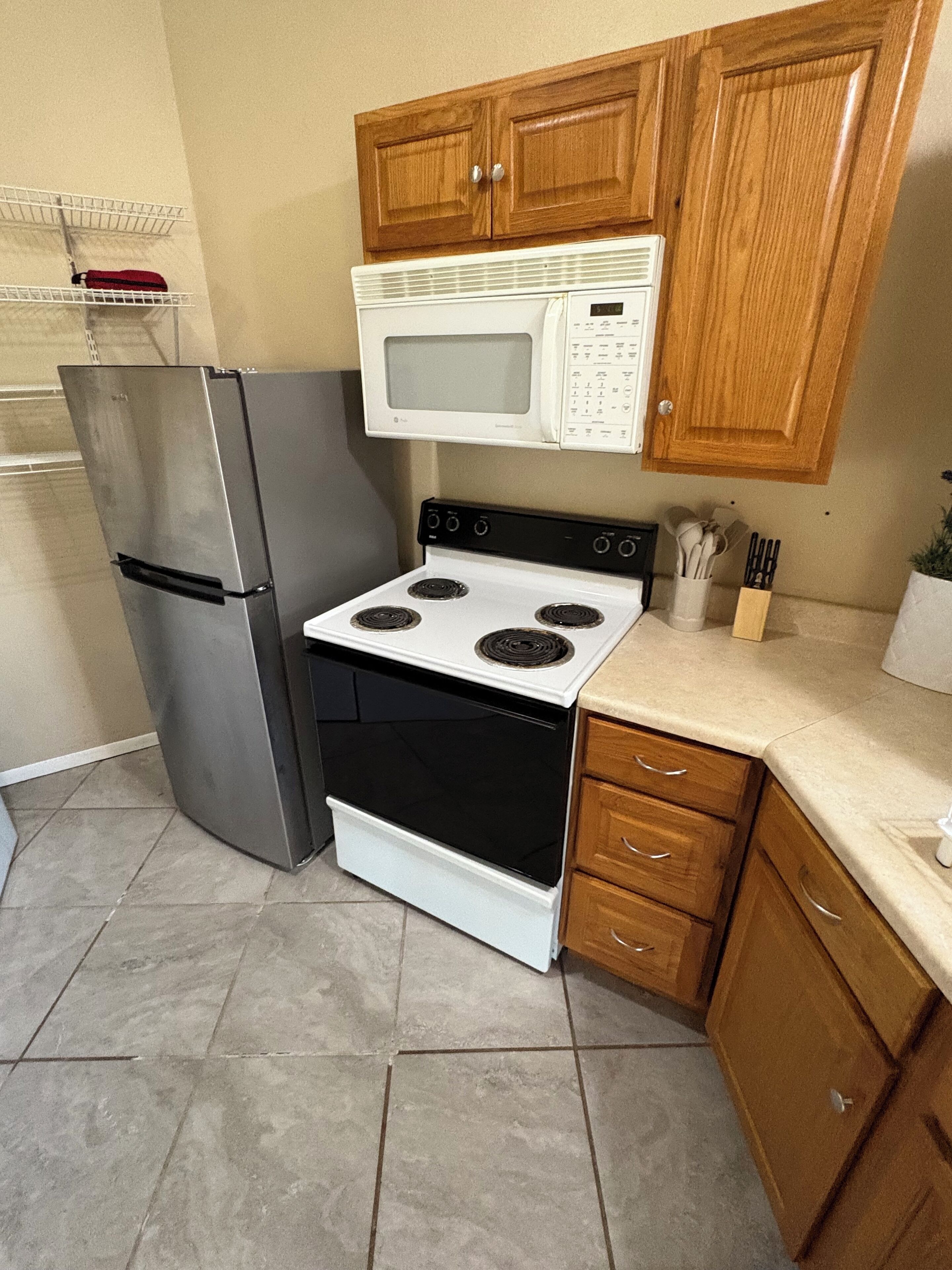 A kitchen with a stainless steel refrigerator, a white stove, and wooden cabinets.