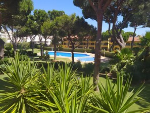 Ein Pool, umgeben von Grünflächen und Gebäuden mit einer gelben Fassade.