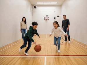 Una cancha de baloncesto con un aro, suelo de madera y pared blanca.