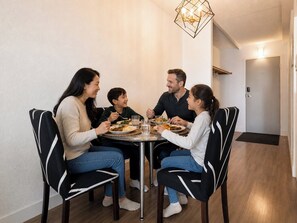 A dining area with a round table, chairs, and a chandelier.