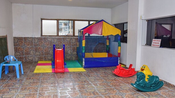 A play area with a small playhouse, a slide, and various toys. - Flat com Piscina e Lazer na Praia de Pitangueiras (Guarujá)