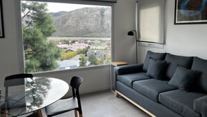 Ein modernes Wohnzimmer mit großem Fenster, einem grauen Sofa und einem Glastisch.