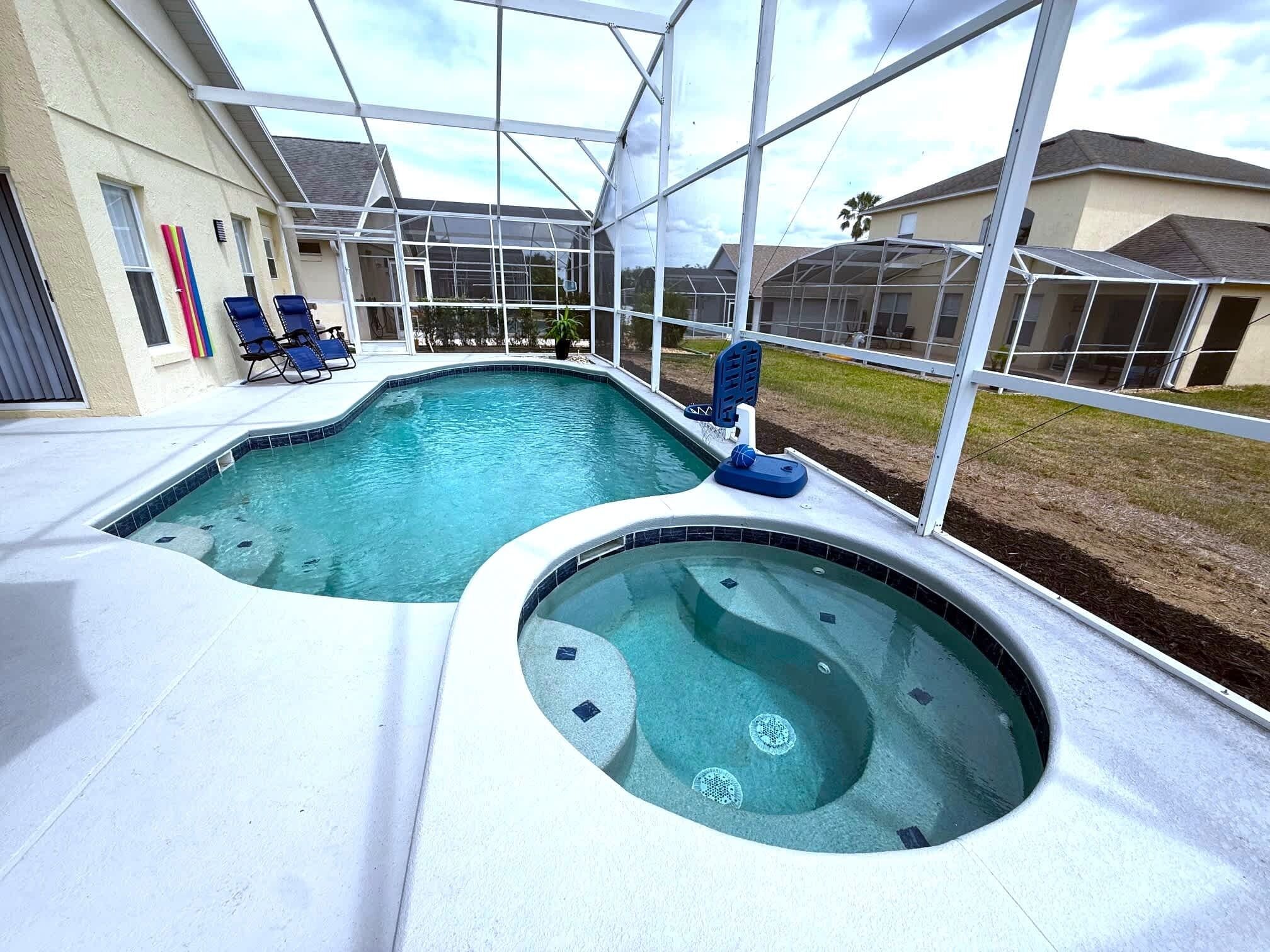 A swimming pool with a hot tub, surrounded by a covered patio with lounge chairs.