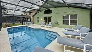 A covered outdoor swimming pool with lounge chairs and a patio area.