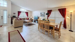 A spacious living room with a sofa, coffee table, and dining area with chairs and a table.
