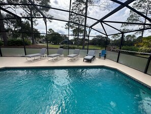 A swimming pool with lounge chairs and a covered area.