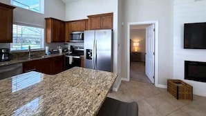 A modern kitchen with granite countertops, stainless steel appliances, and wooden cabinets. - South Facing Updated Southern Dunes Villa (Haines City)