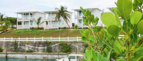 A coastal hotel with a white fence, a dock, and a boat.