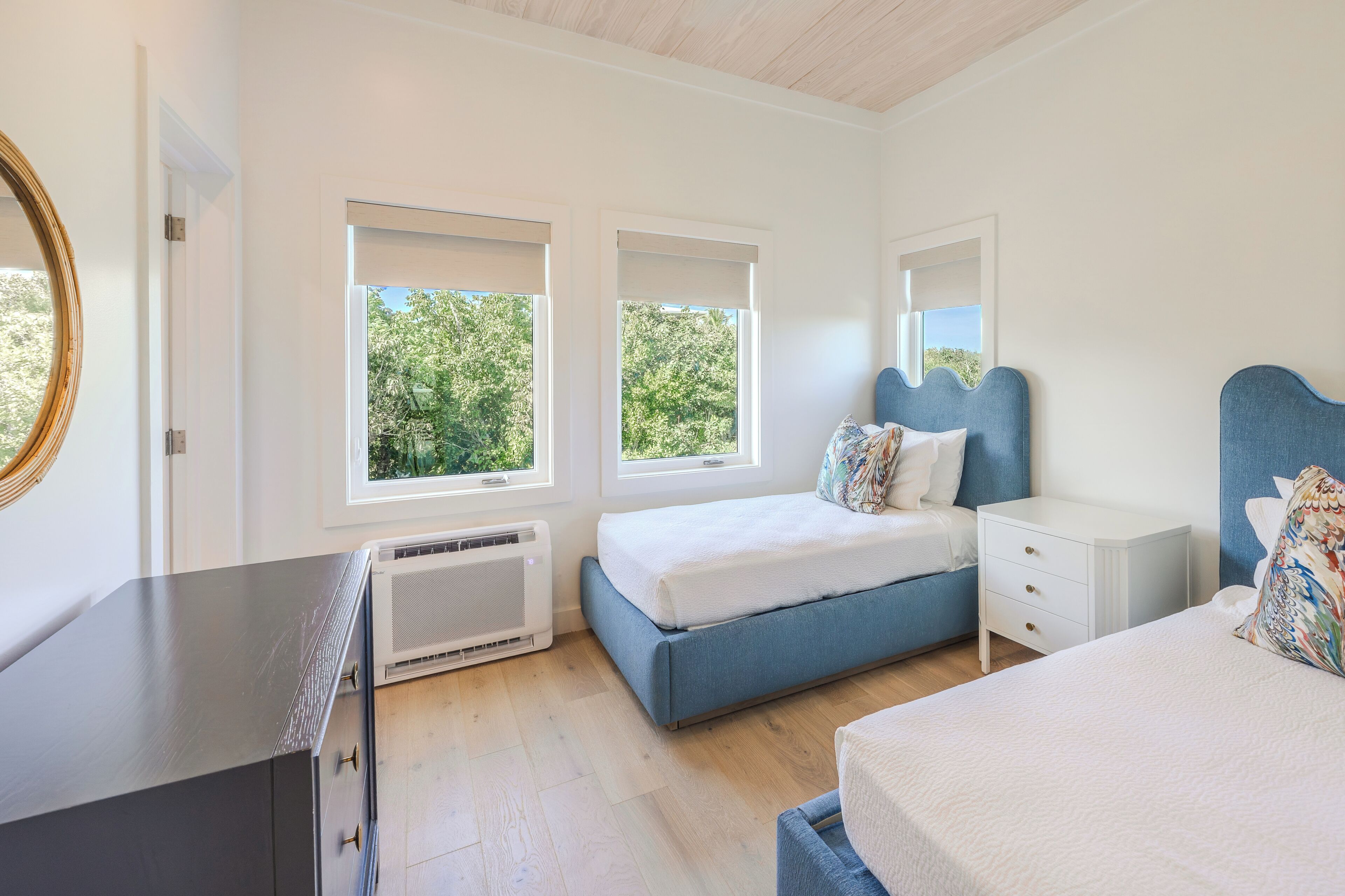 A bedroom with a bed, bedside tables, a dresser, and a window.