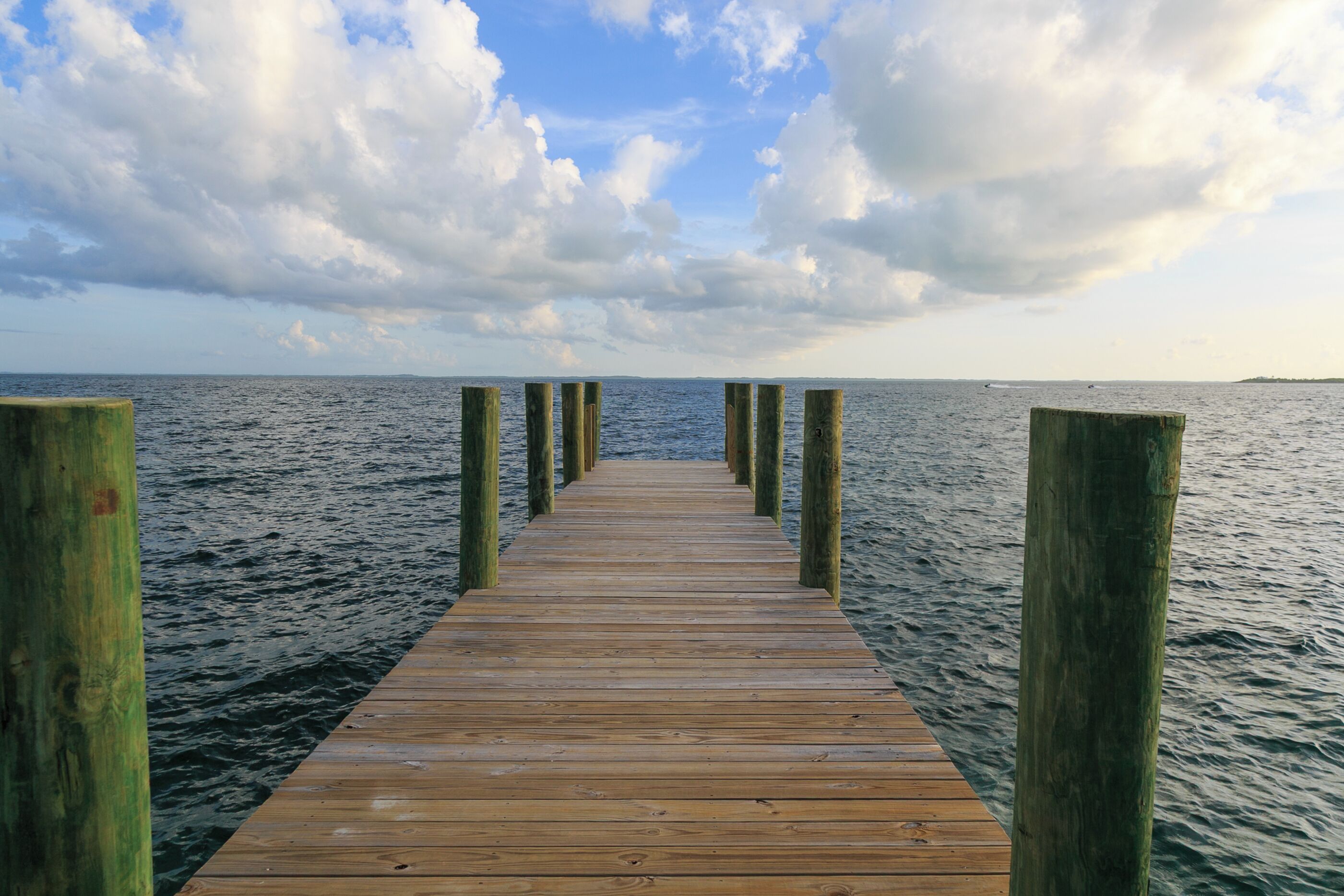 A wooden pier extending into calm waters with a clear sky above.
