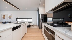Une cuisine moderne avec des meubles blancs, un îlot central et un four encastré.
