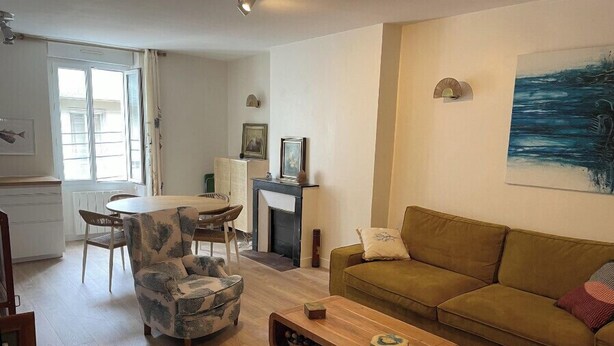 A living room with a sofa, a coffee table, a dining table with chairs, and a fireplace. - Renovated apartment - near beach (Dinard)