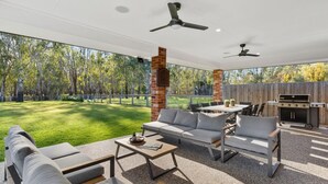 Une terrasse extérieure avec un canapé, des chaises, une table et un barbecue.