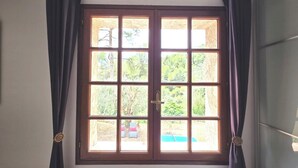 A room with a large window, curtains, and a radiator.