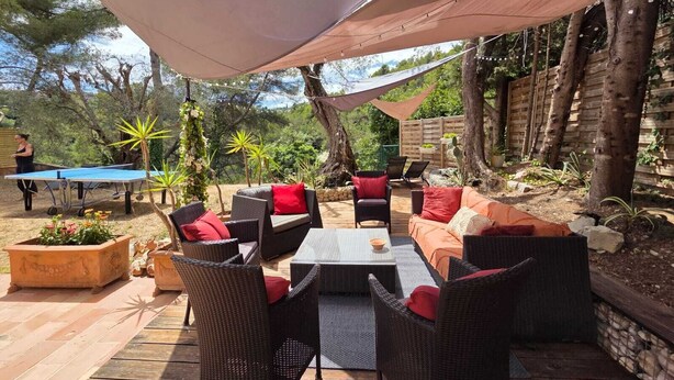 An outdoor patio with wicker furniture, a ping pong table, and a shaded area.