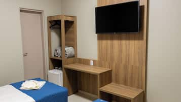 A hotel room with two beds, a TV mounted on the wall, and a wooden wardrobe.