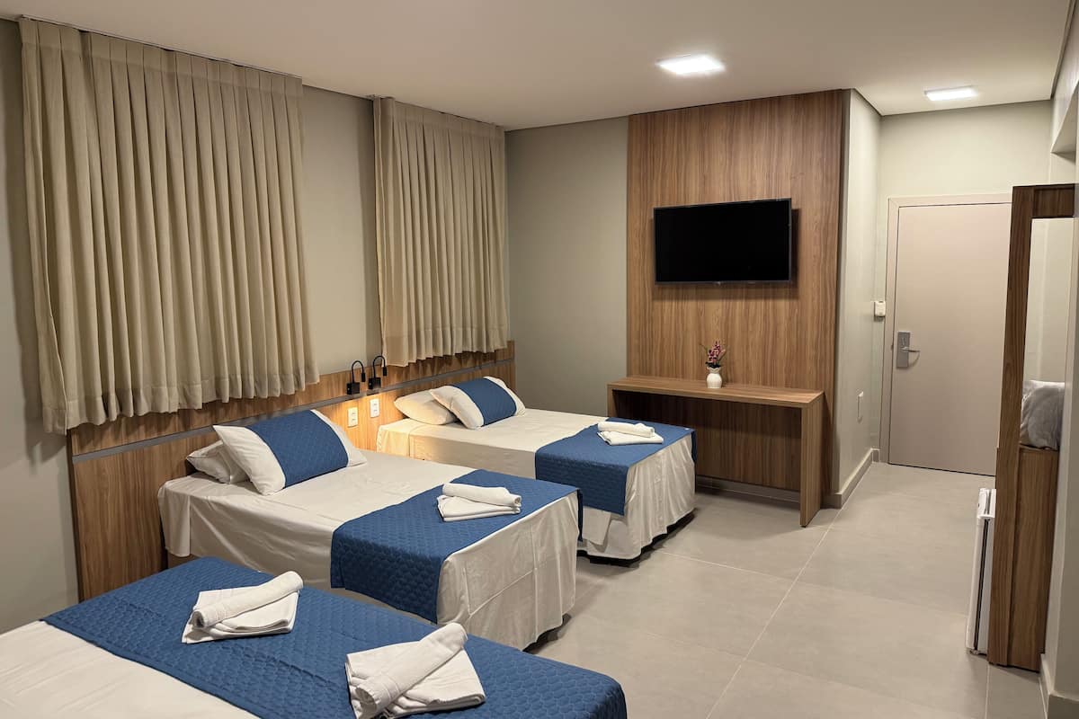 Ett hotellrum med två sängar, en TV som är monterad på väggen och en träpaneldesign.