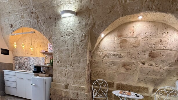 Une pièce aux murs de pierre, avec un lit, une petite table et des chaises.