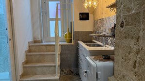 Une cuisine avec un mur en pierre, un four encastré et un escalier menant à une porte.