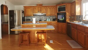Une cuisine moderne avec des meubles en bois, des appareils en acier inoxydable, un îlot central doté de tabourets et des fenêtres de toit.