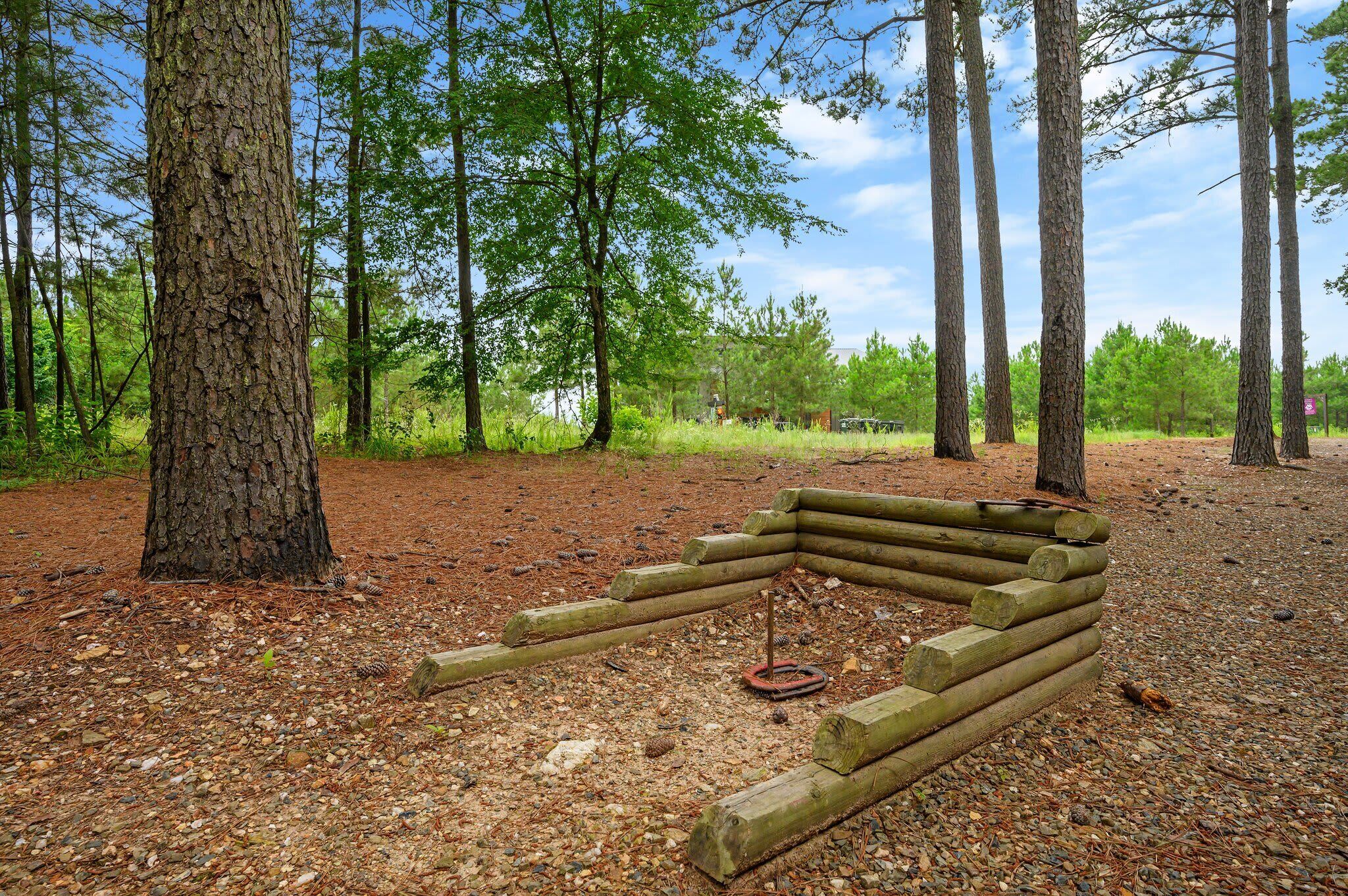A forested area with a wooden bench and a metal spiral sculpture.