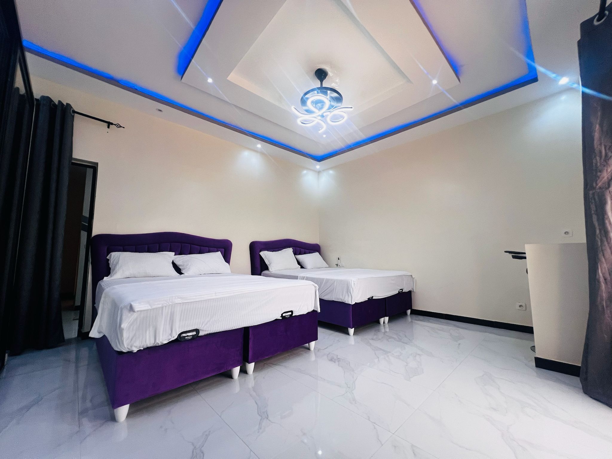 A modern bedroom with two beds, a ceiling light fixture, and a marble floor.