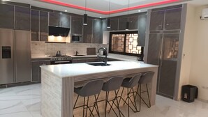 A modern kitchen with a central island, stainless steel appliances, and a red accent lighting strip.