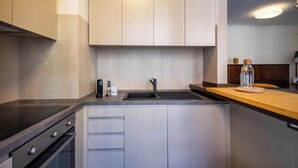 A modern kitchen with a stainless steel stove, a sink, and white cabinetry.