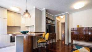 A modern kitchen with a wooden island, bar stools, and pendant lighting.