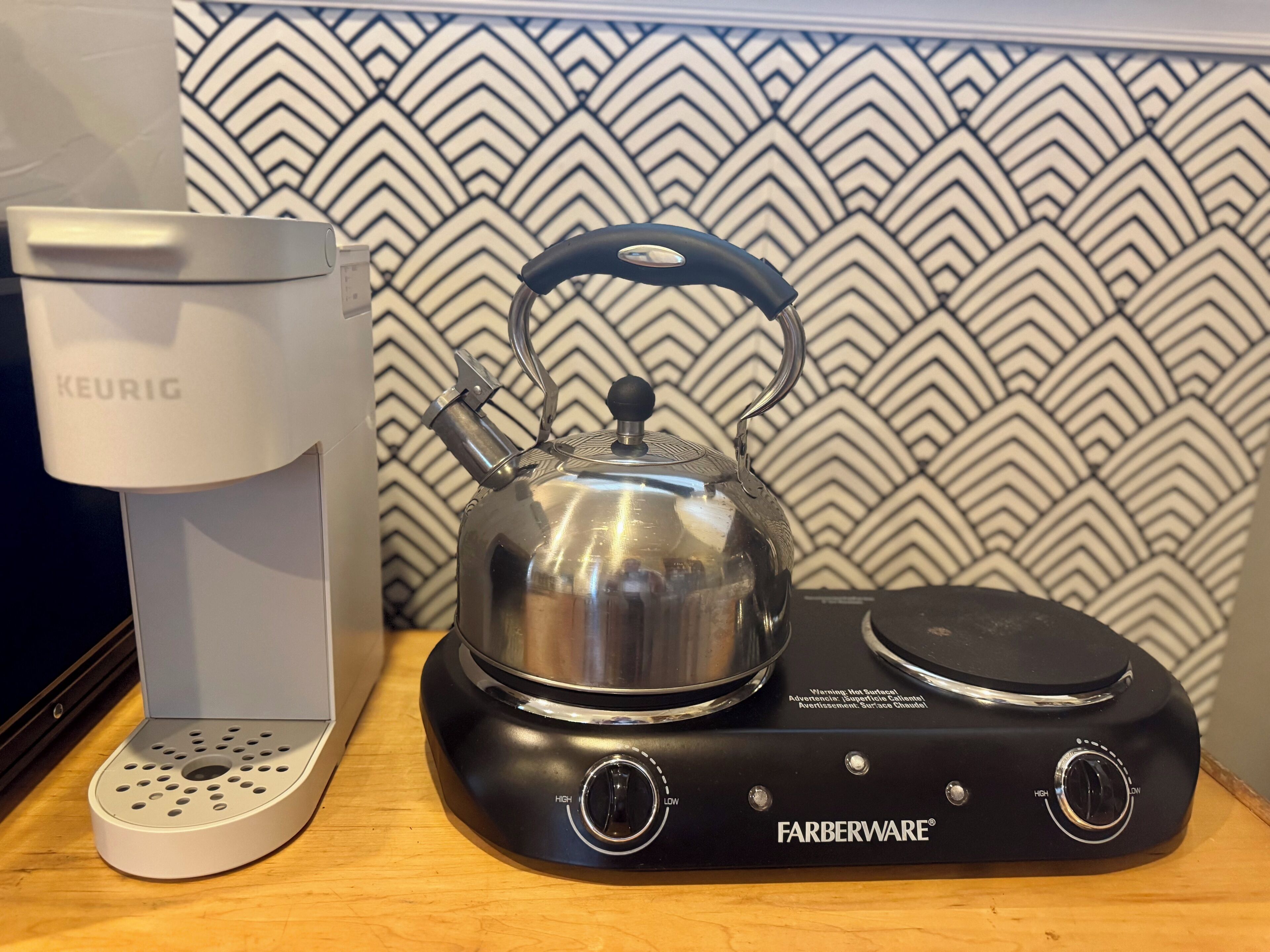 A Farberware electric kettle and a Keurig coffee maker on a wooden surface.