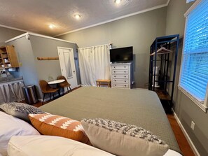 Un dormitorio con cama, escritorio, silla, televisor y armario.