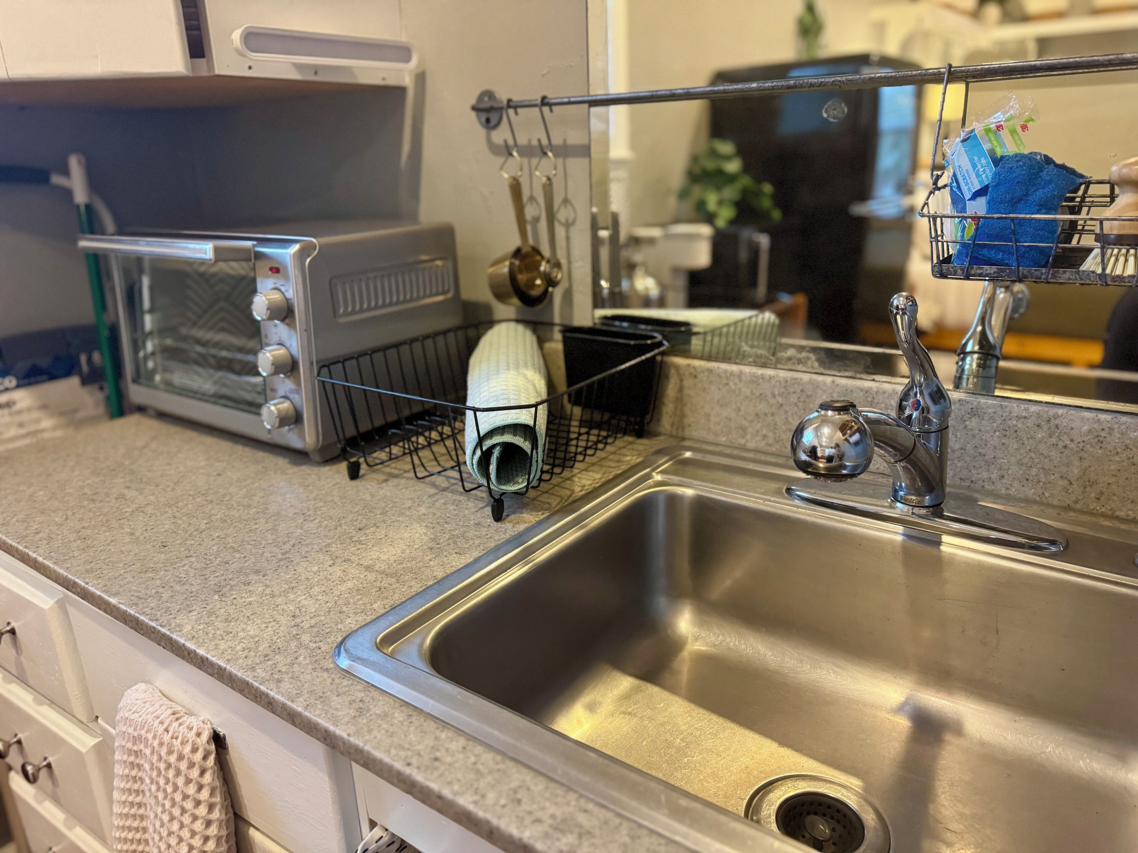 A kitchen with a stainless steel sink, a toaster, and a dish rack.