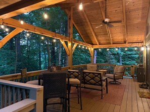 Eine überdachte Holzterrasse mit Holzbalken, Lichterketten und Sitzbereichen.