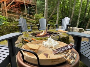 A round wooden table with a fire pit, surrounded by Adirondack chairs. - Tree Top Mountain Lodge (Cullowhee)