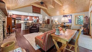 A spacious living area with a wooden ceiling, a dining table, and a kitchen in the background. - Tree Top Mountain Lodge (Cullowhee)