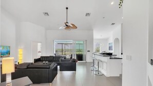 A spacious living area with a modern sofa, a dining table, and a kitchen area with a bar.