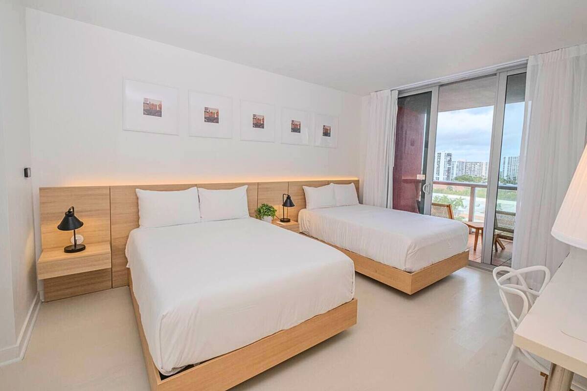 Une chambre d’hôtel avec deux lits, une petite table, une chaise et un balcon avec vue.