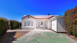 Una casa de un solo piso con fachada blanca y tejado de tejas rojas.