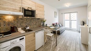 Une cuisine moderne équipée d’un lave-linge, d’un four à micro-ondes et d’un coin repas avec une table et des chaises.