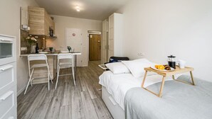 Une chambre d’hôtel de taille réduite comprenant un lit, une petite kitchenette, un coin repas et une salle de bain.