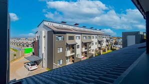 A modern apartment building with multiple balconies and a car parked in front. - Bukkie’s loft place (Sandton)