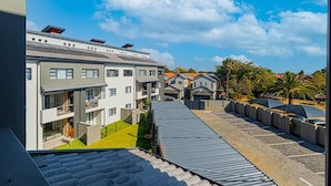 A residential building with multiple balconies, a parking area, and a clear sky. - Bukkie’s loft place (Sandton)