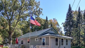 En lille, etetagers bygning med en veranda og et flagstang med det amerikanske flag.