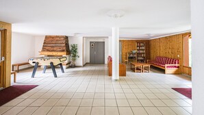 A spacious room with a foosball table, a bookshelf, a sofa, and a door marked with an 'A'.