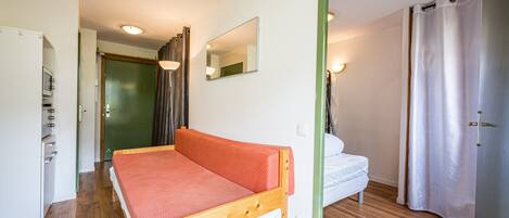 A room with a wooden bed, a white sofa, a mirror, and a green-framed door.