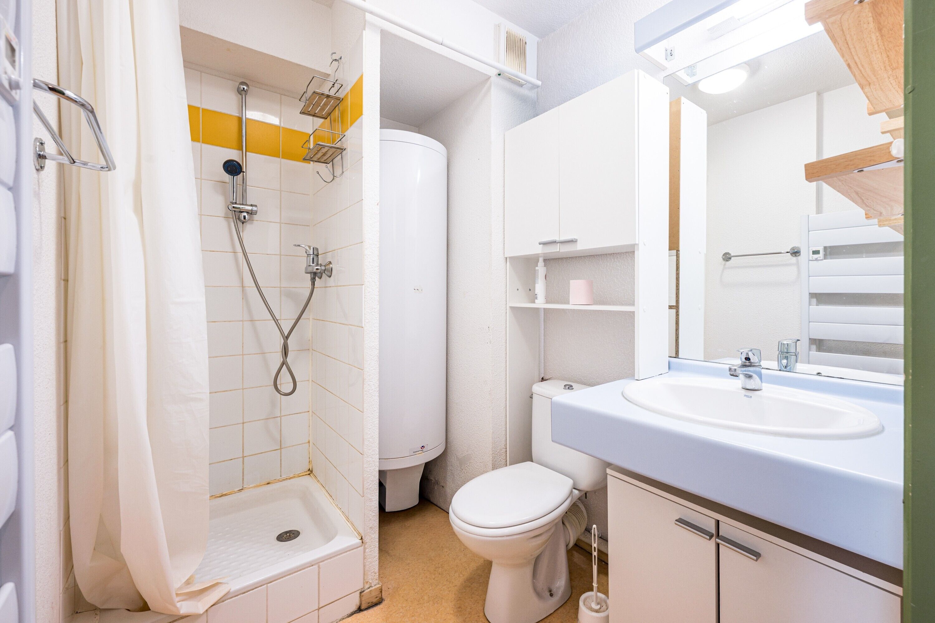 A bathroom with a shower, toilet, sink, and mirror.