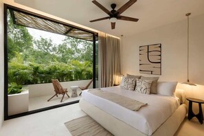 Un dormitorio moderno con una cama grande, un ventilador de techo, vistas a zonas verdes y una decoración minimalista.