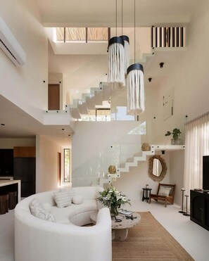 A spacious living area with a white sofa, a coffee table, and a staircase. - Casa Cascada Jungle Villa Beach Club Access (Tulum)