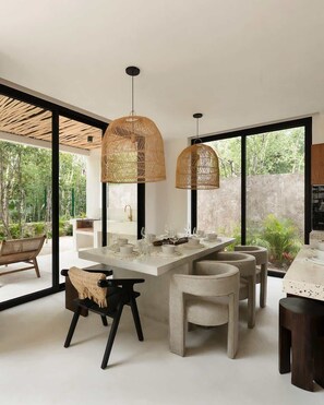 Una cocina moderna con una isla central, luces colgantes y ventanas amplias.